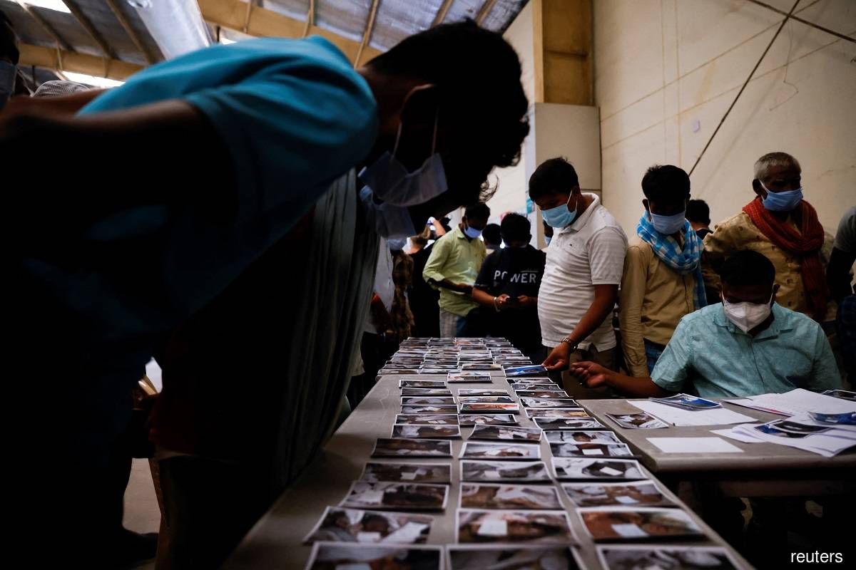 People look at pictures to identify the bodies of victims of a train collision, at a temporary mortuary created in a business park, following the train collision in Balasore district in the eastern state of Odisha, India June 4, 2023. (Reuters pic)